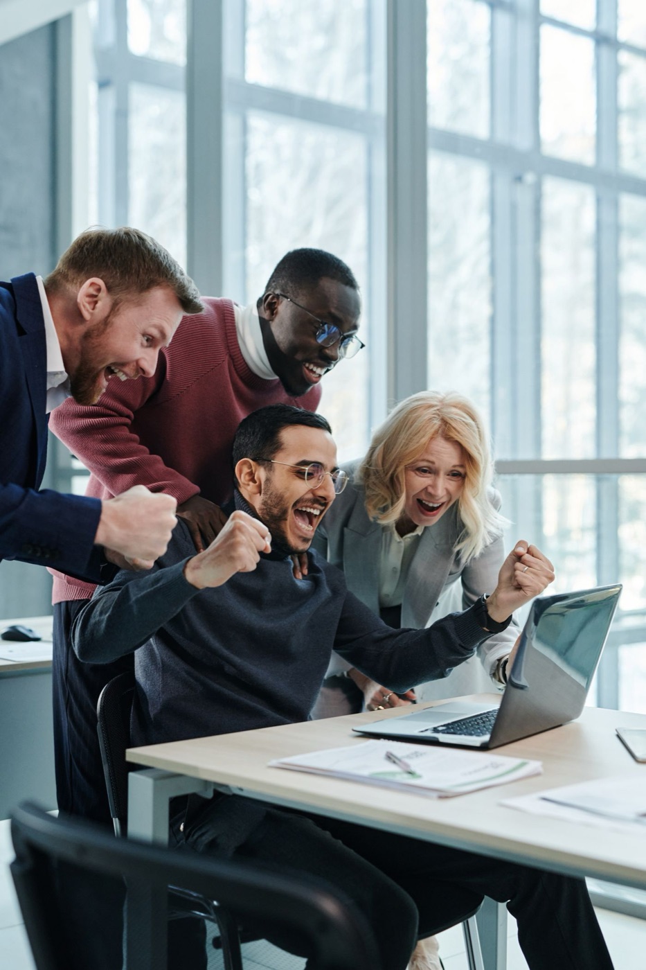A team cheering at a laptop as their website works again